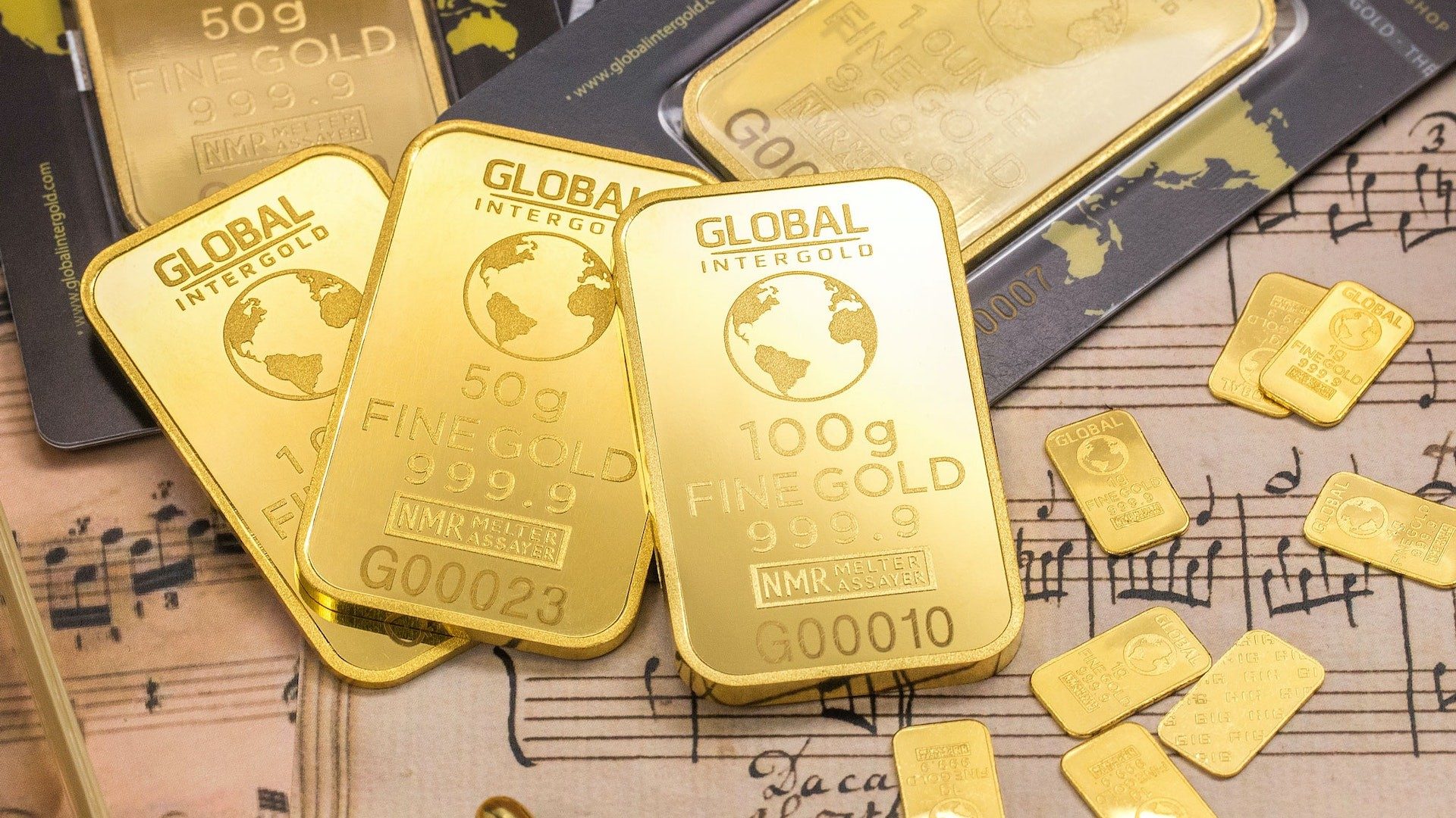 Goldbarren verschiedener Größen auf einem Musik-Notenblatt