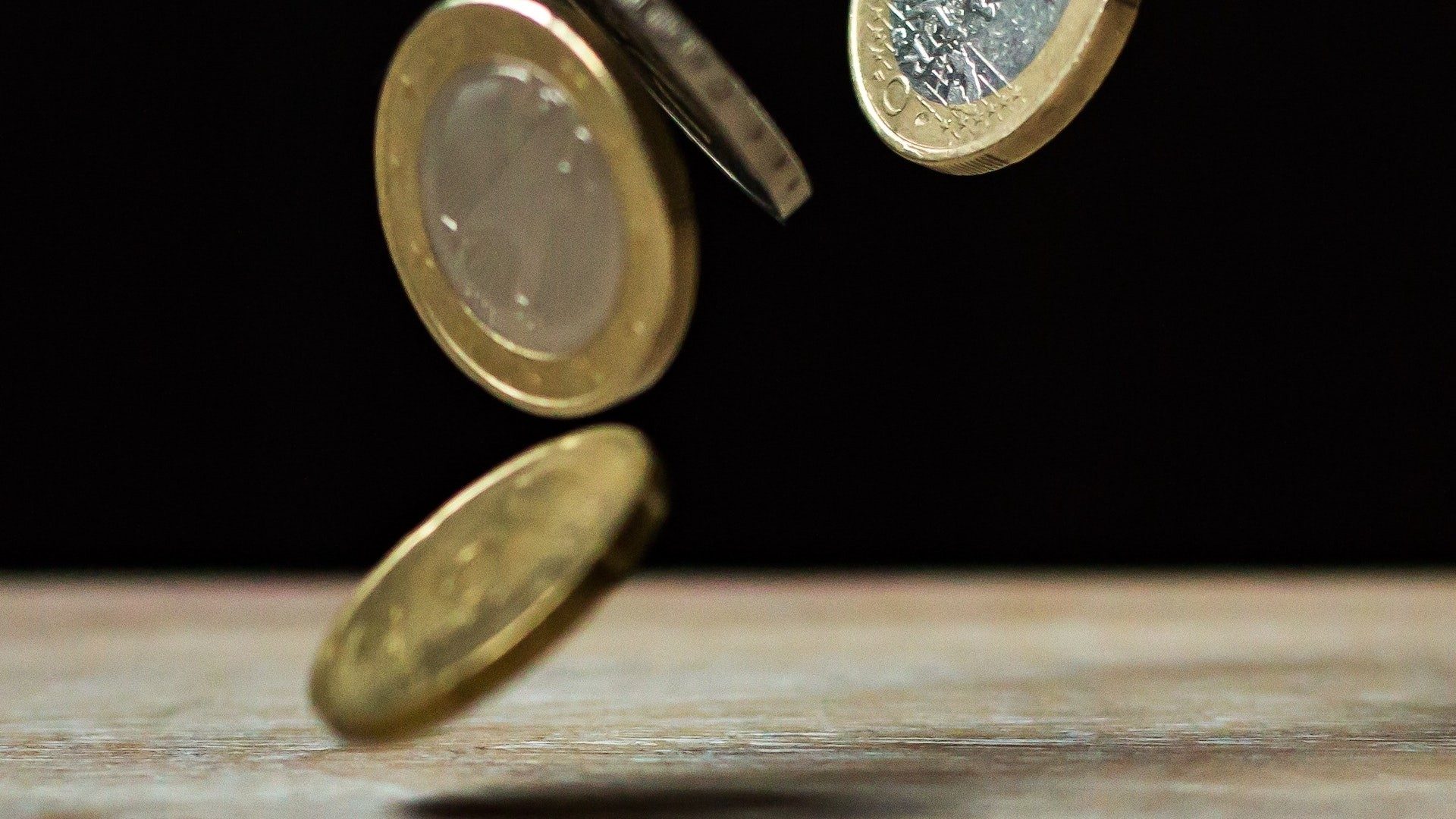 Euro-Münzen fallen auf einen Holztisch