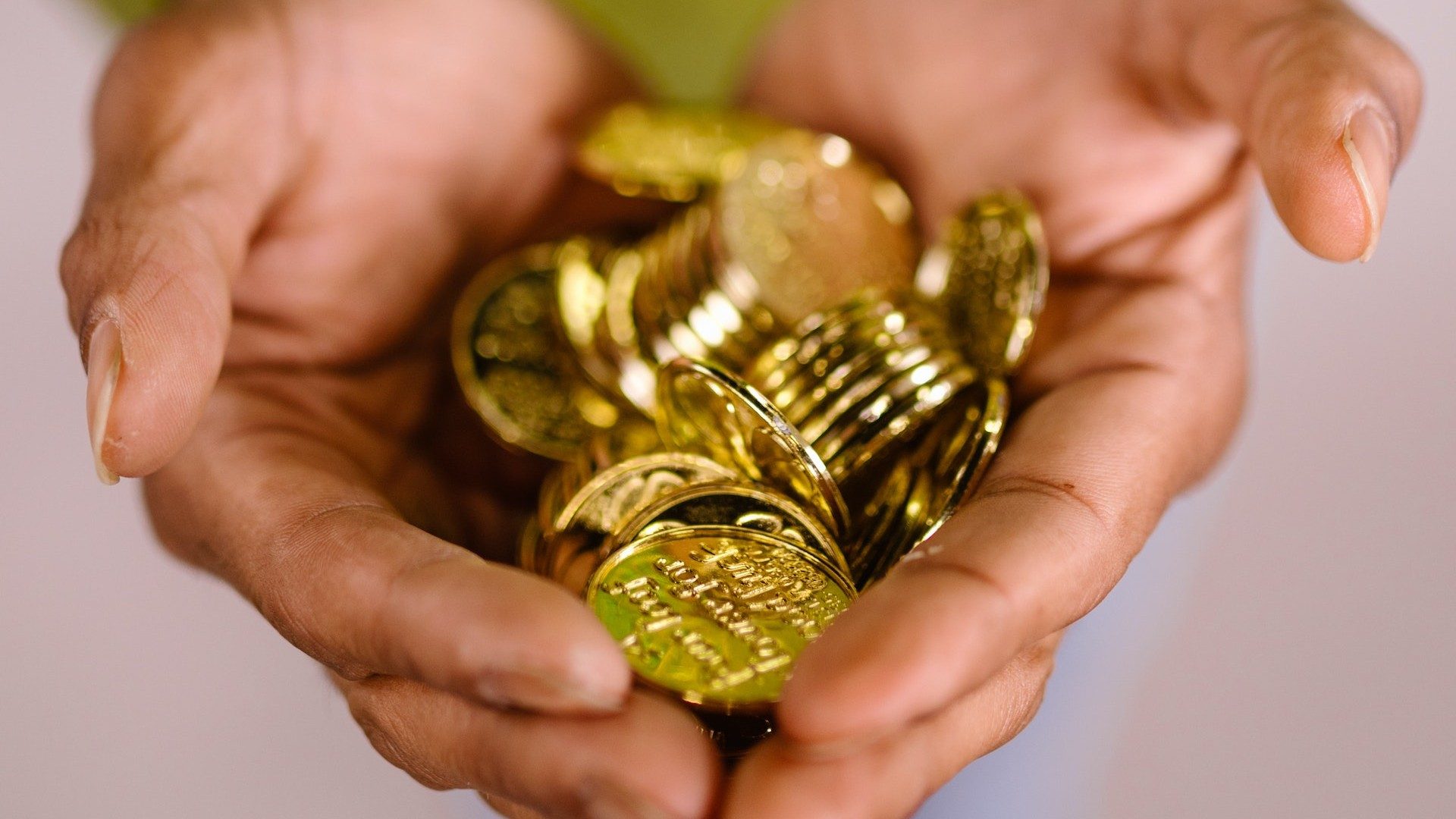 Eine Person hält eine Vielzahl von Goldmünzen in ihren Händen