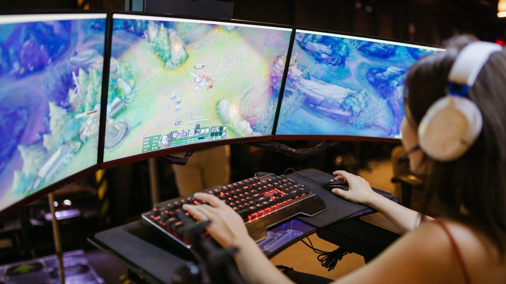 Eine Frau spielt das Computerspiel "League of Legends" auf drei Bildschirmen