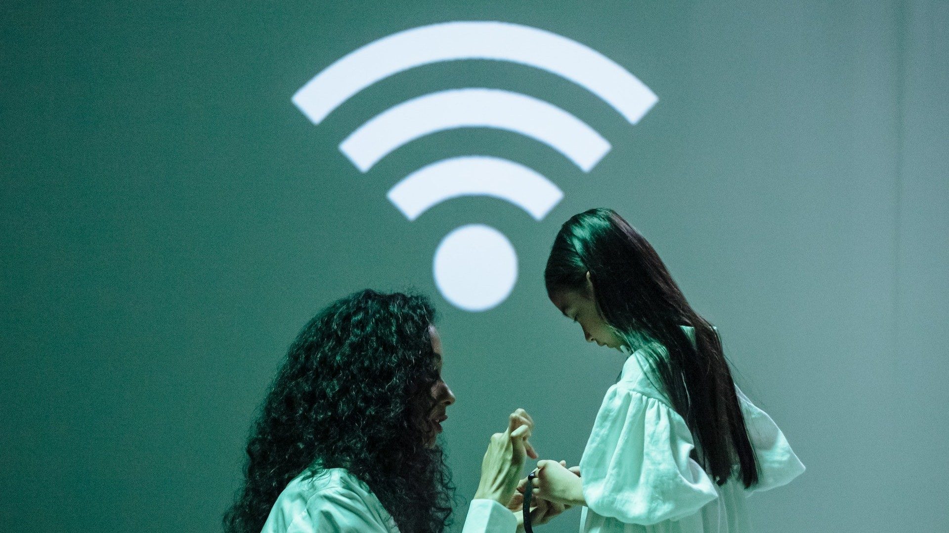 Eine Frau und ein Kind verbinden eine Smartwatch mit dem Internet, darüber ein großes WLAN-Empfangs-Symbol