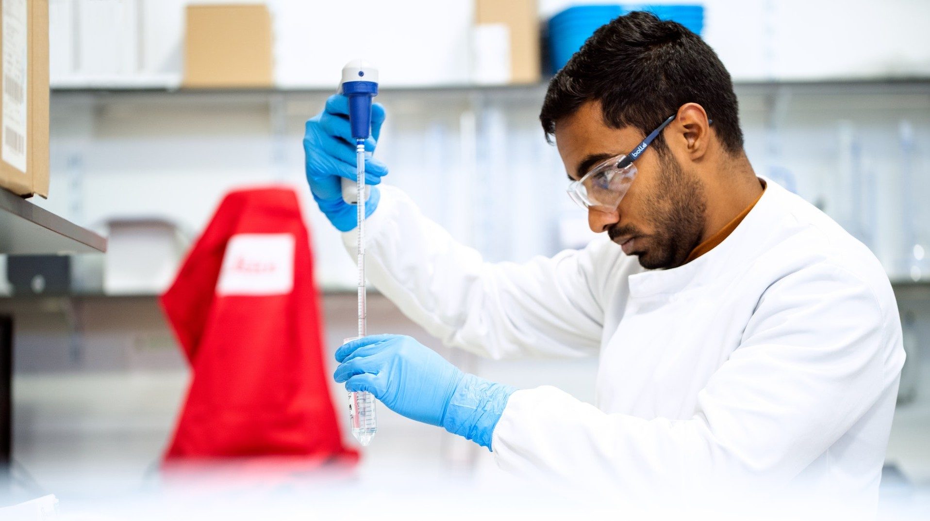 Ein Forscher arbeitet mit Pipette und Reagenzglas im Labor