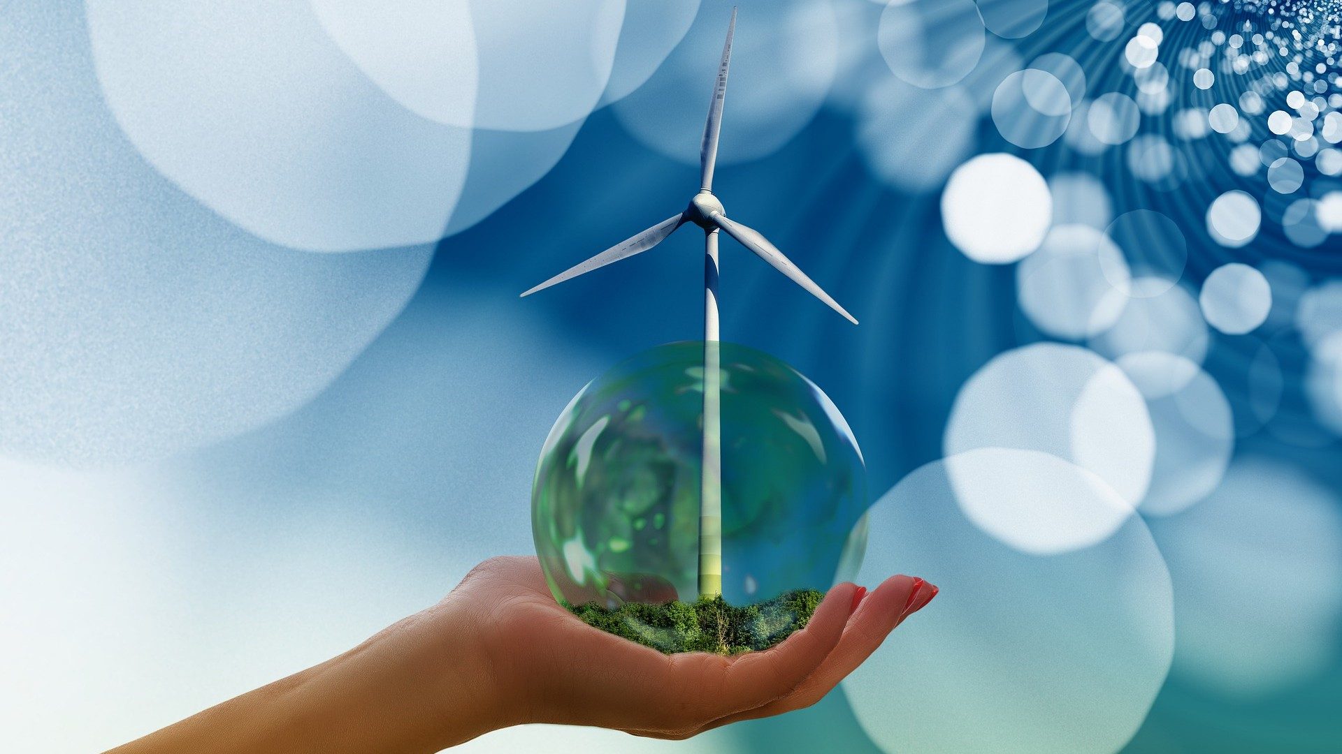Nachhaltige Energie: Eine Hand hält eine grüne Blase mit einem Windrad darin