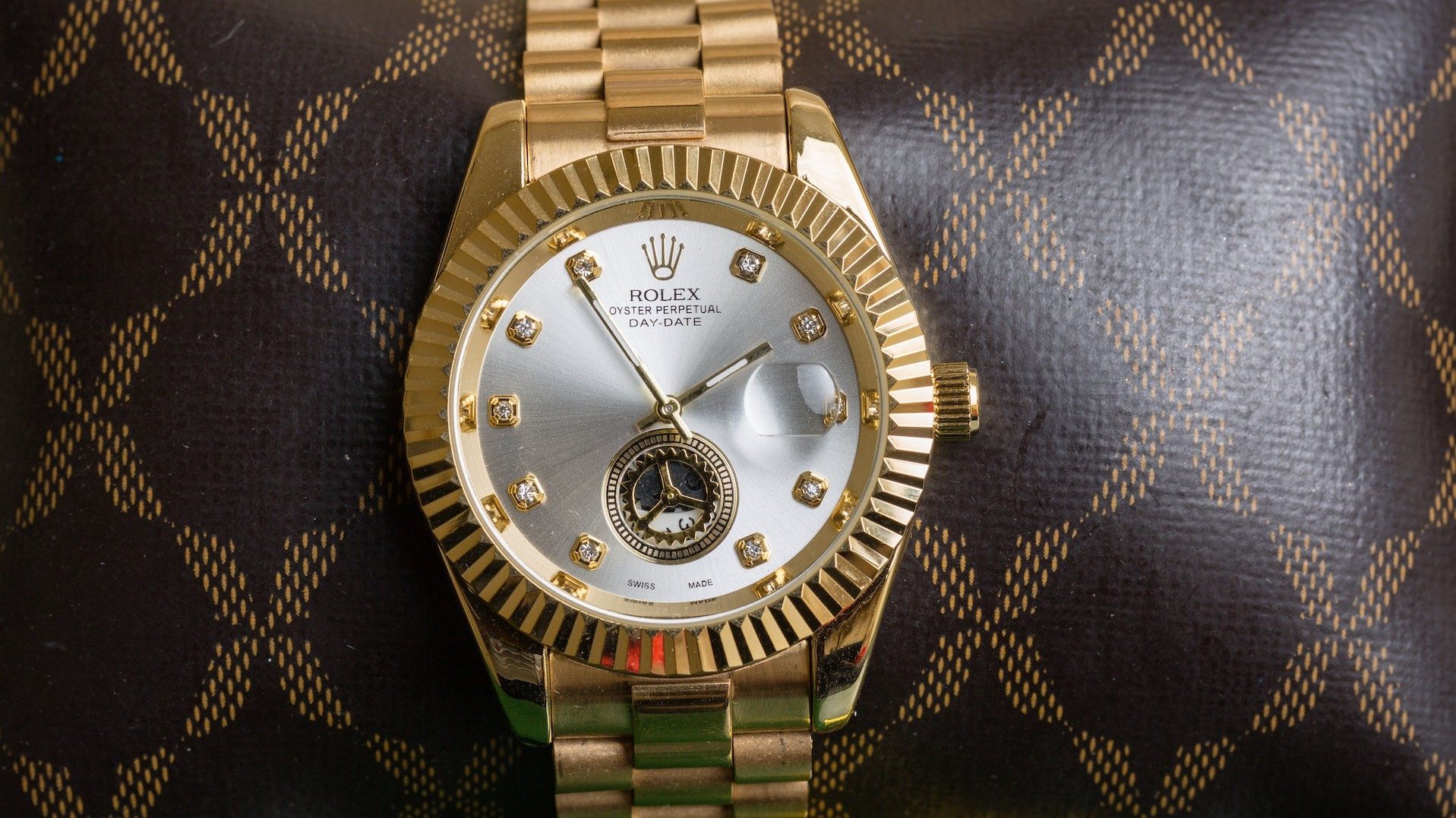 Eine Rolex-Armbanduhr vor einem typischen Louis-Vuitton-Muster