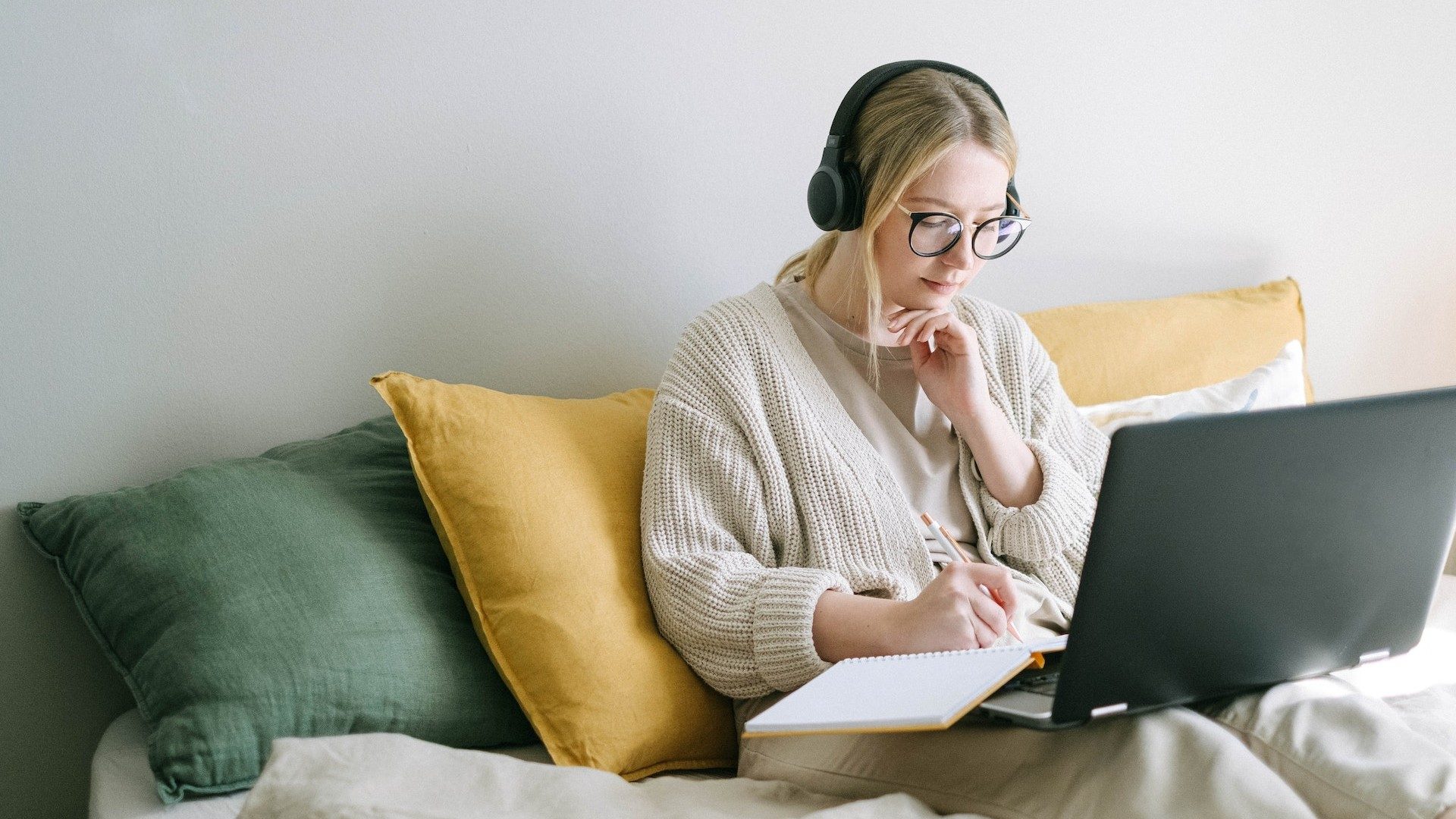 Eine Frau sitzt auf der Couch an ihrem Laptop und arbeitet