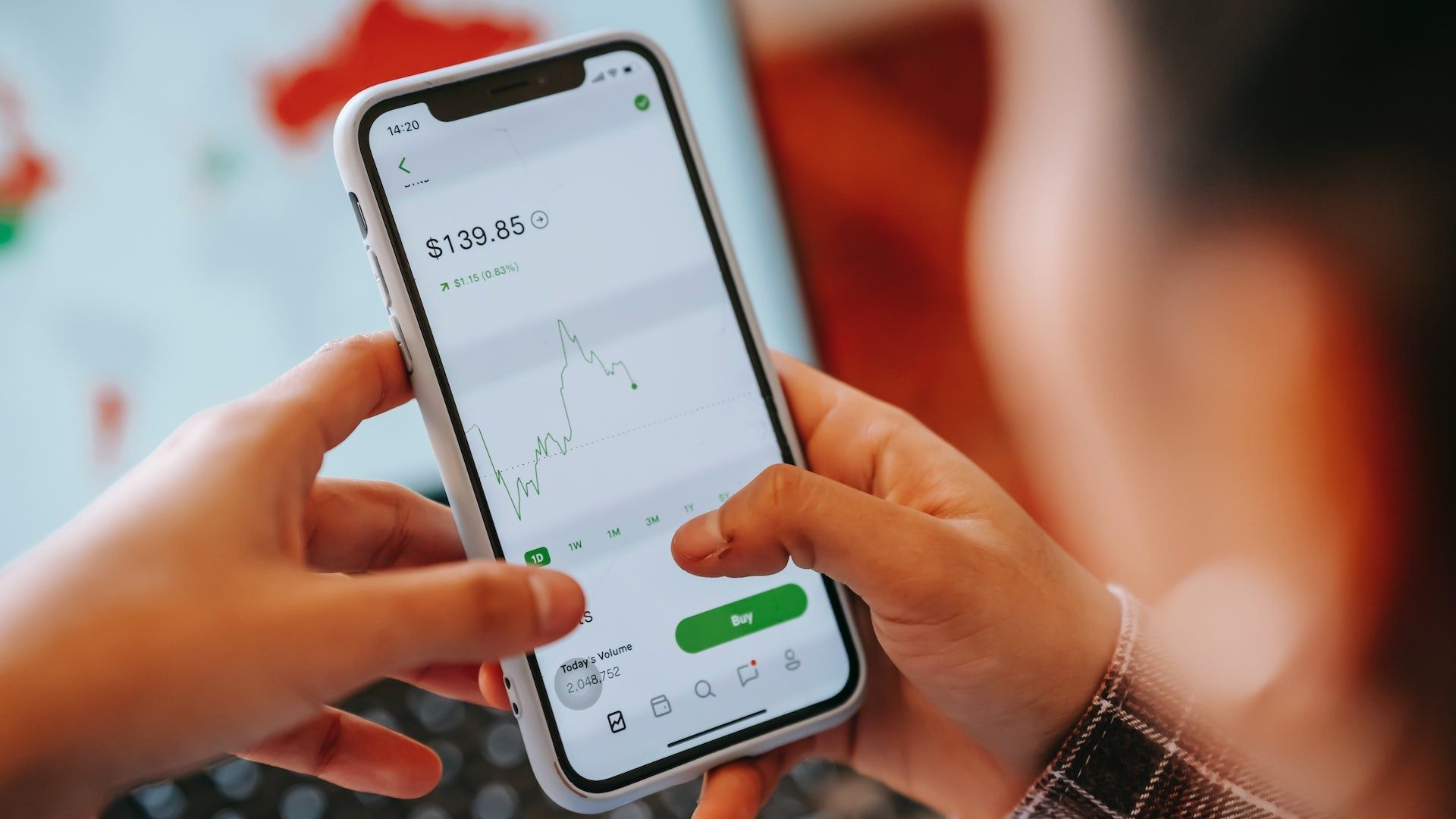 Eine Person hält ihr Smartphone mit einer geöffneten Trading-App