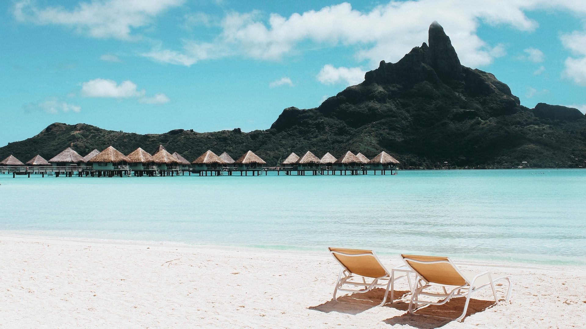 Zwei Liegestühle auf einem traumhaften einsamen Strand im Paradies