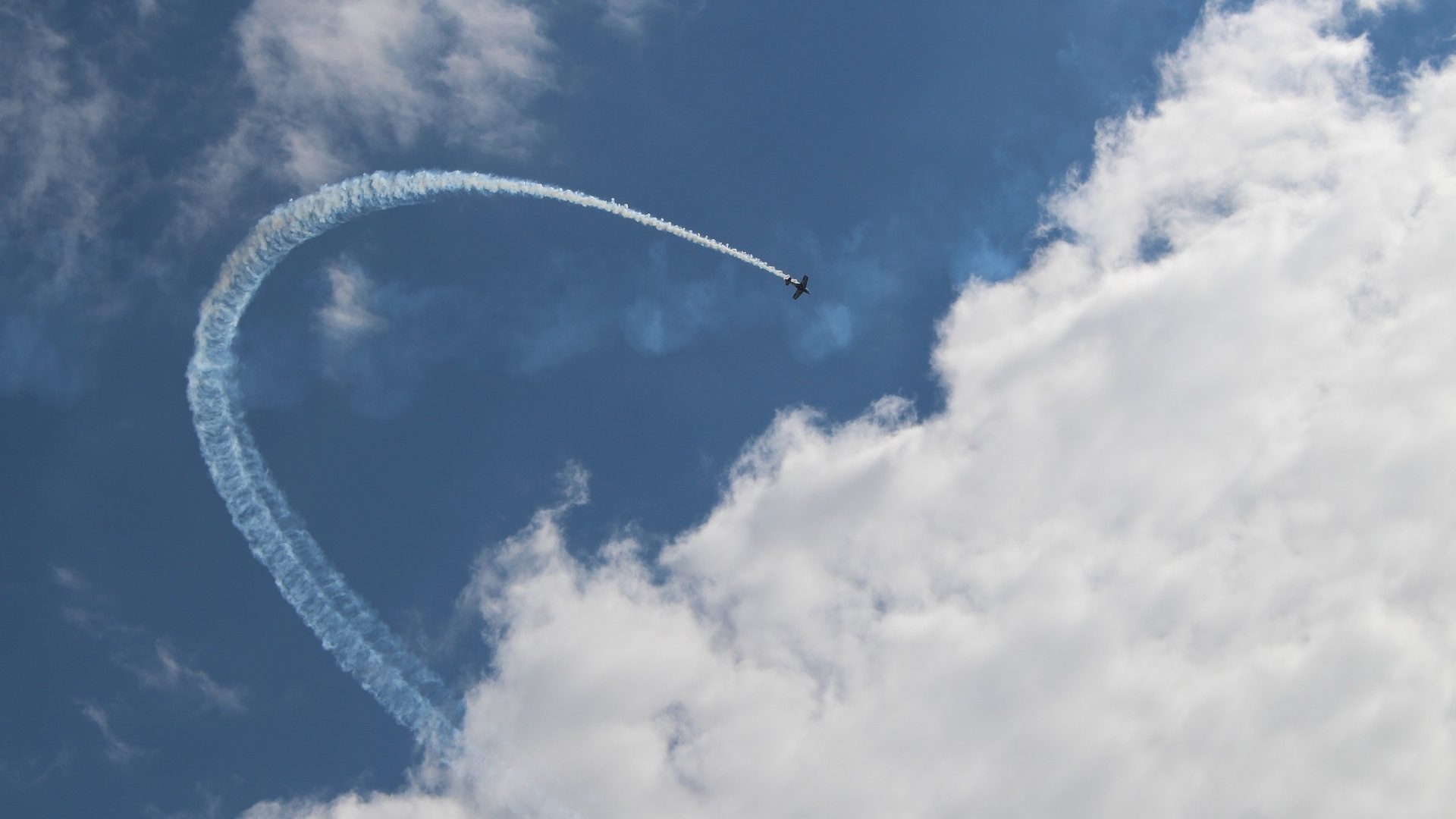 Ein Sportflugzeug fliegt einen Looping und hinterlässt weißen Rauch