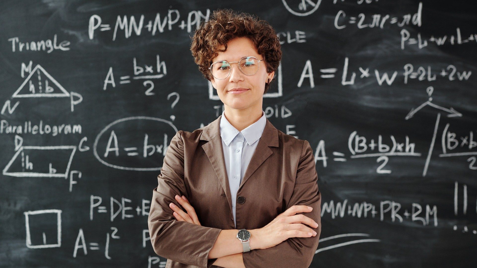 Eine Lehrerin steht vor einer Tafel voller mathematischer Formeln