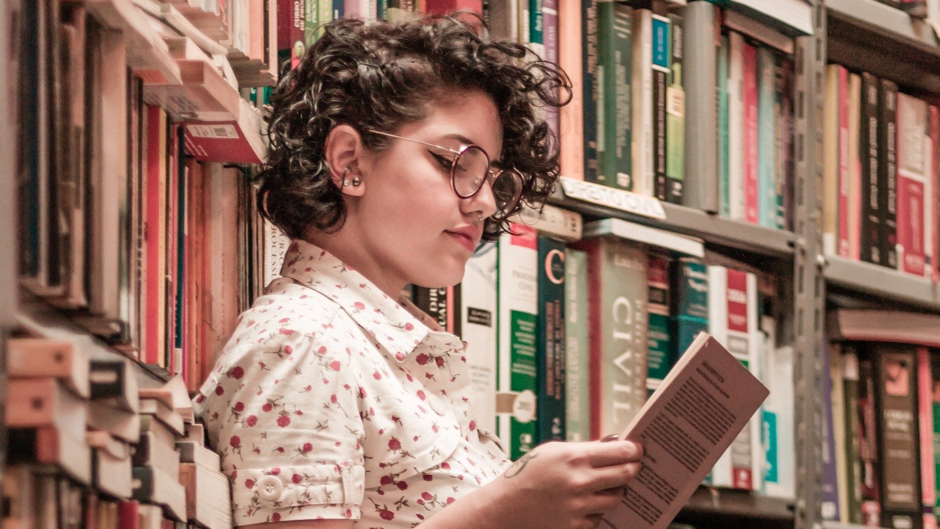 Eine junge Frau liest in einer Bibliothek aus einem Buch