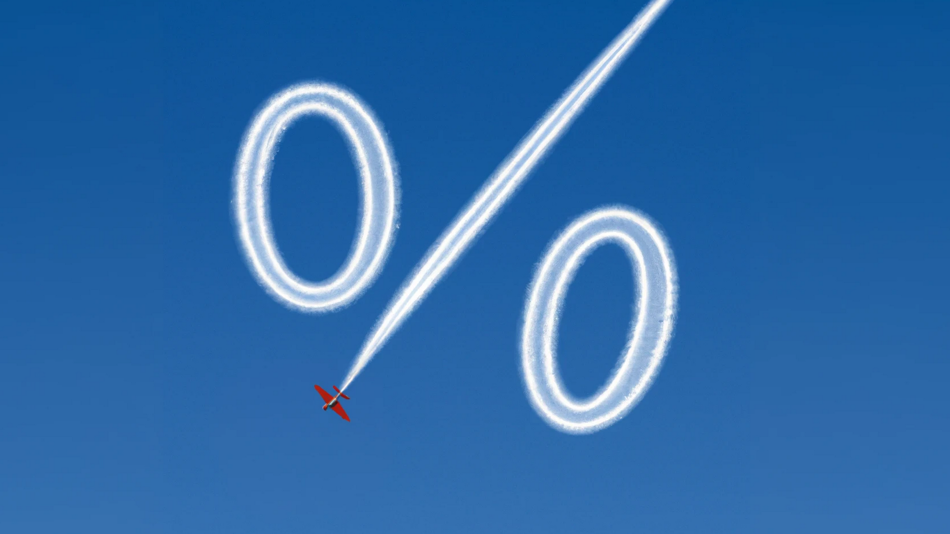 Ein Sportflugzeug zeichnet mit weißem Rauch ein Prozent-Zeichen in den blauen Himmel