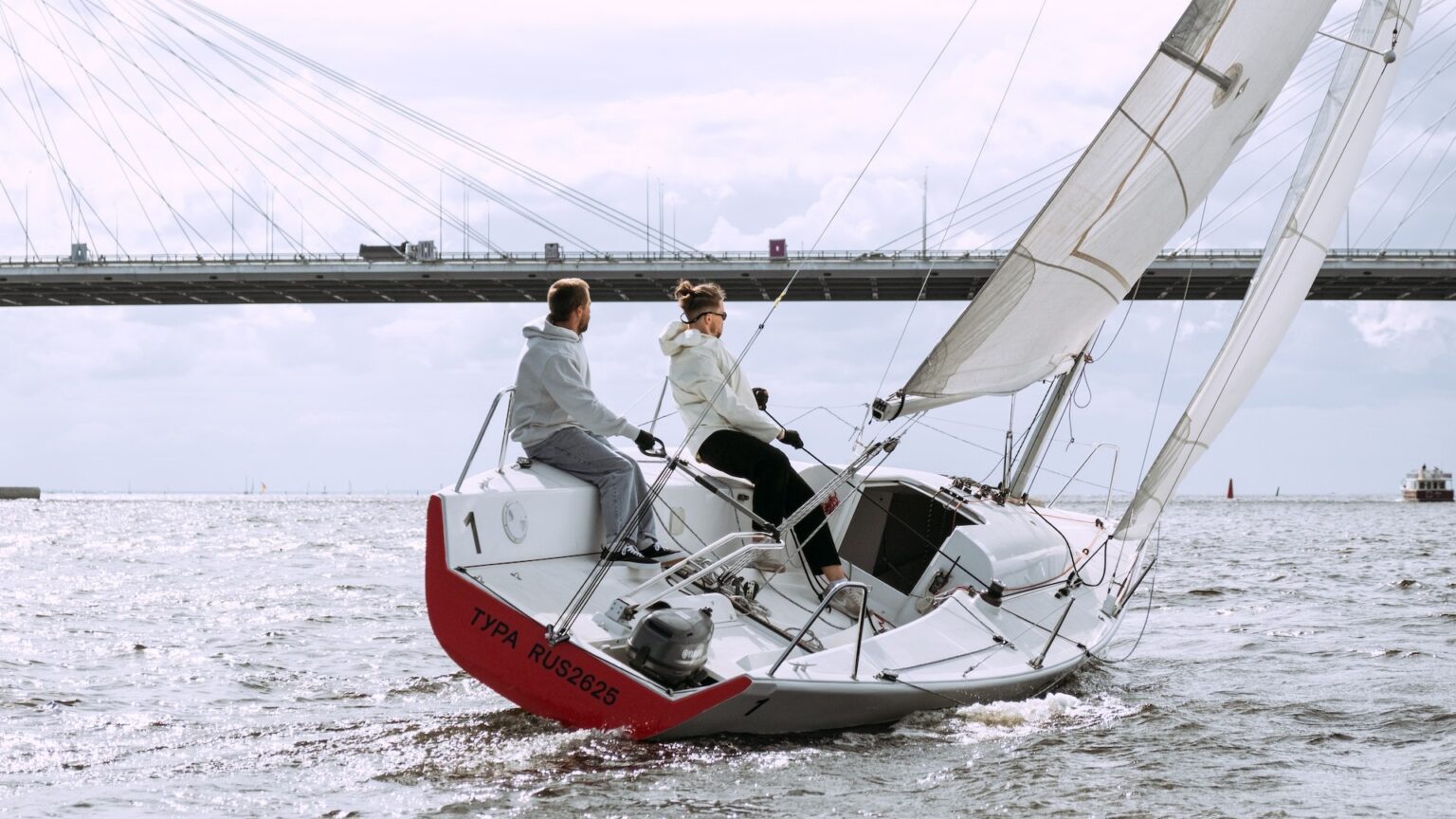 Zwei Männer steuern ihr Segelboot durch ein Gewässer