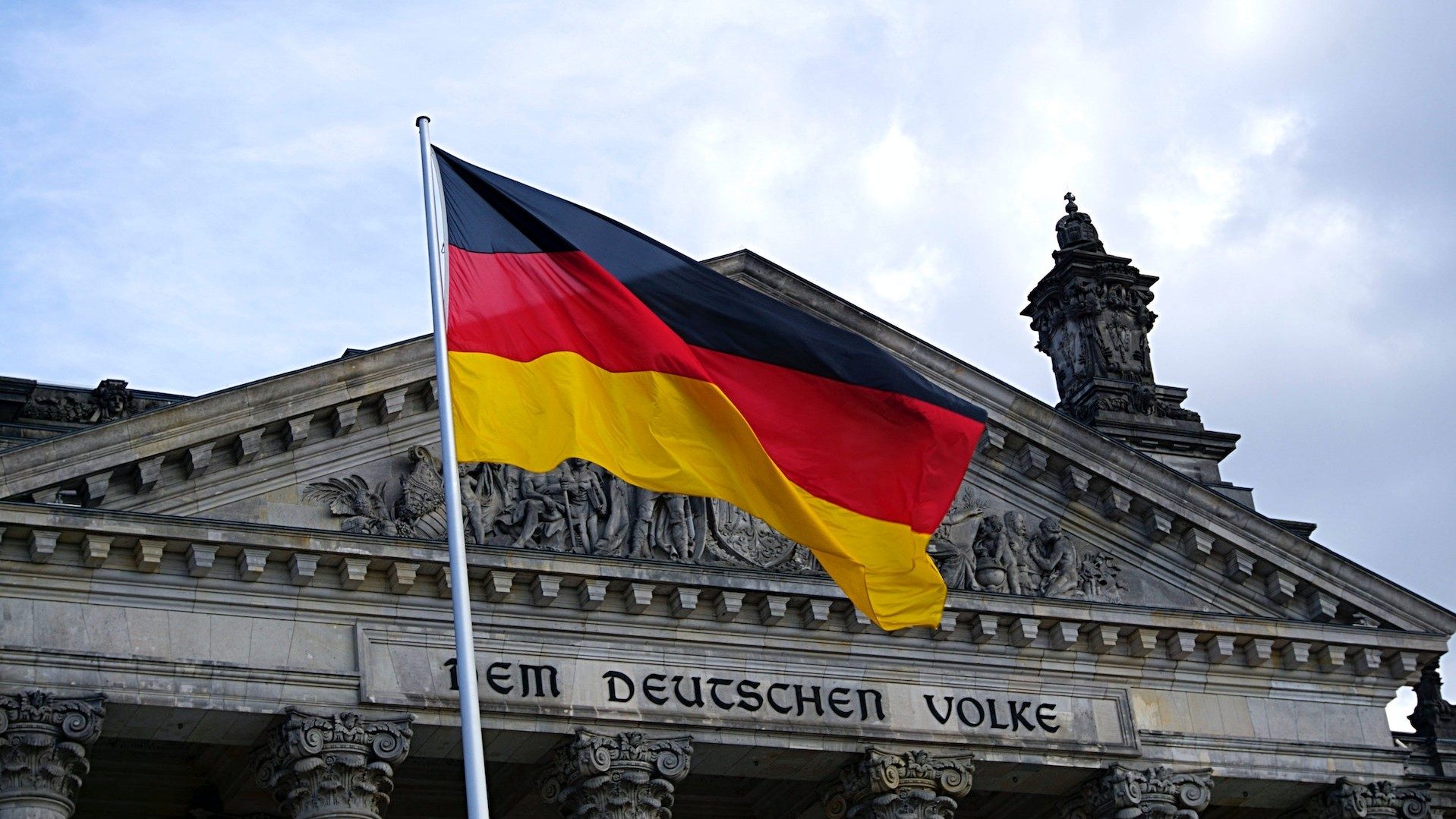 Die deutsche Fahne vor dem Schriftzug "Dem Deutschen Volke" am Reichstagsgebäude