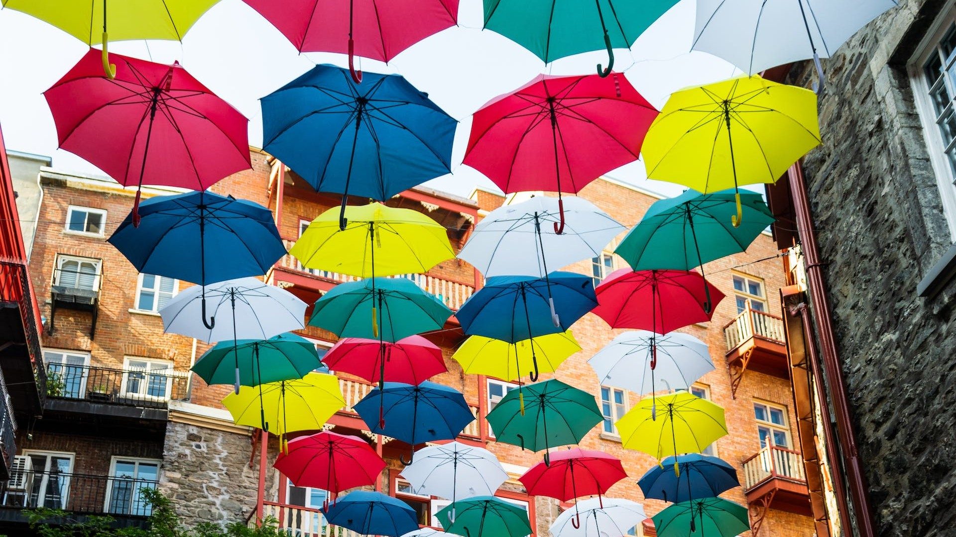Viele bunte Regenschirme in einer alten Gasse