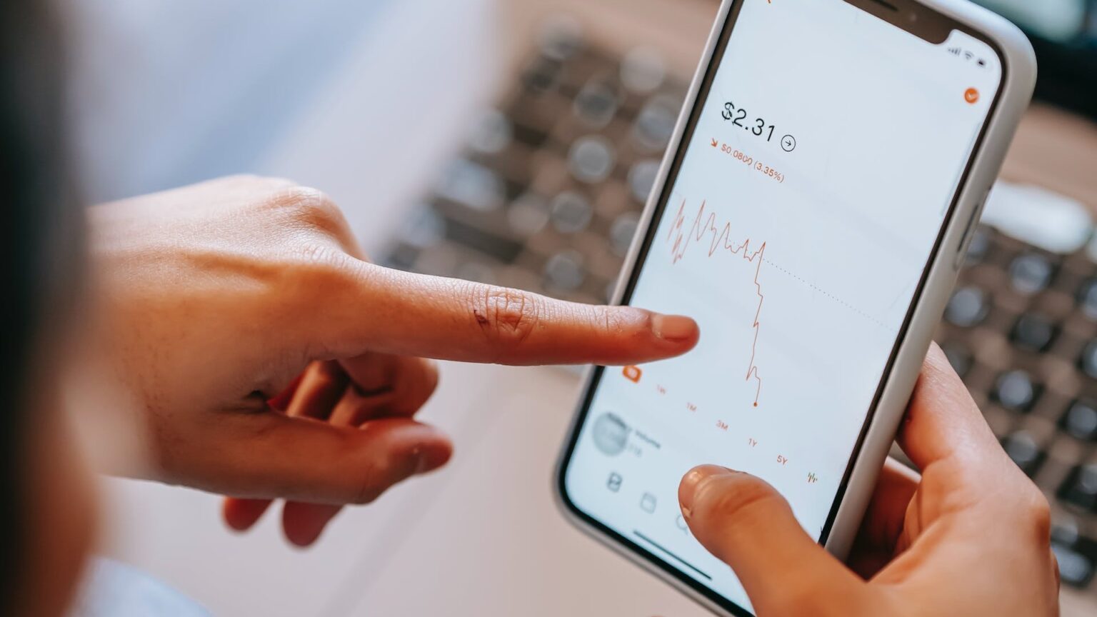 Eine Person betrachtet auf dem Smartphone einen fallenden Aktienkurs