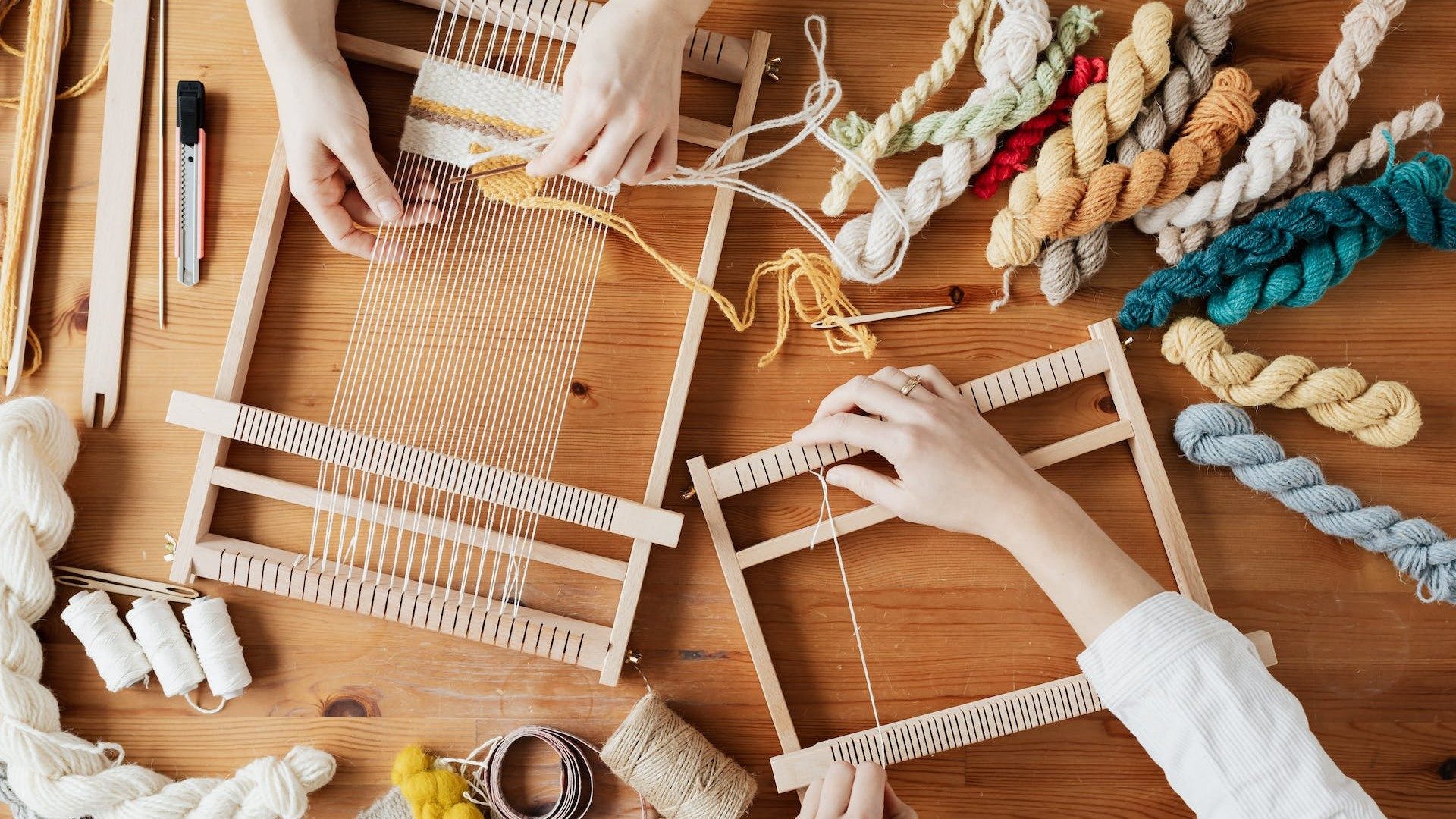 Zwei Personen weben ein DIY-Projekt auf einem Mini-Webstuhl