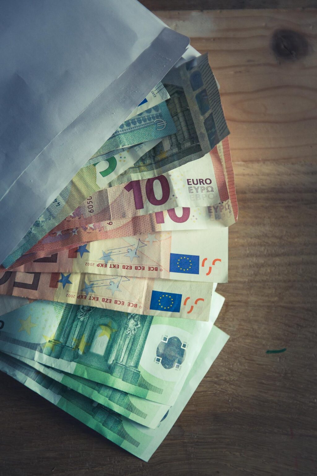 Euro-Geldscheine und ein Umschlag liegen auf dem Tisch
