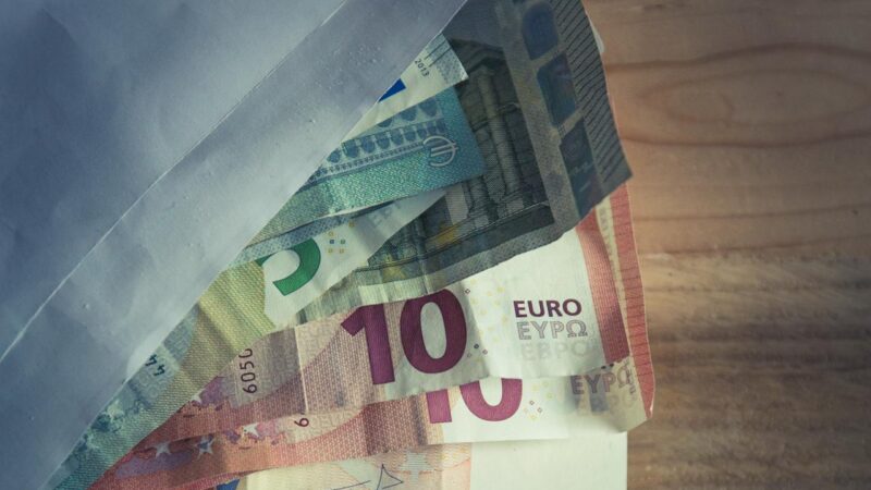 Euro-Geldscheine und ein Umschlag liegen auf dem Tisch