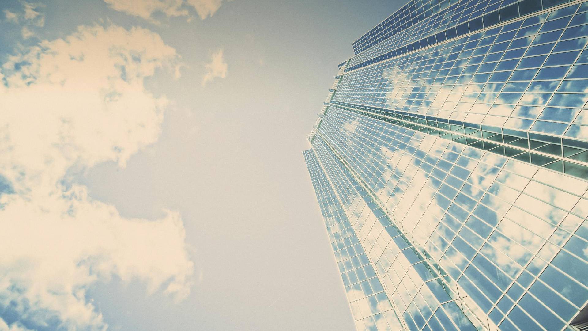 Ein gläsernes Hochhaus kratzt am blauen Himmel