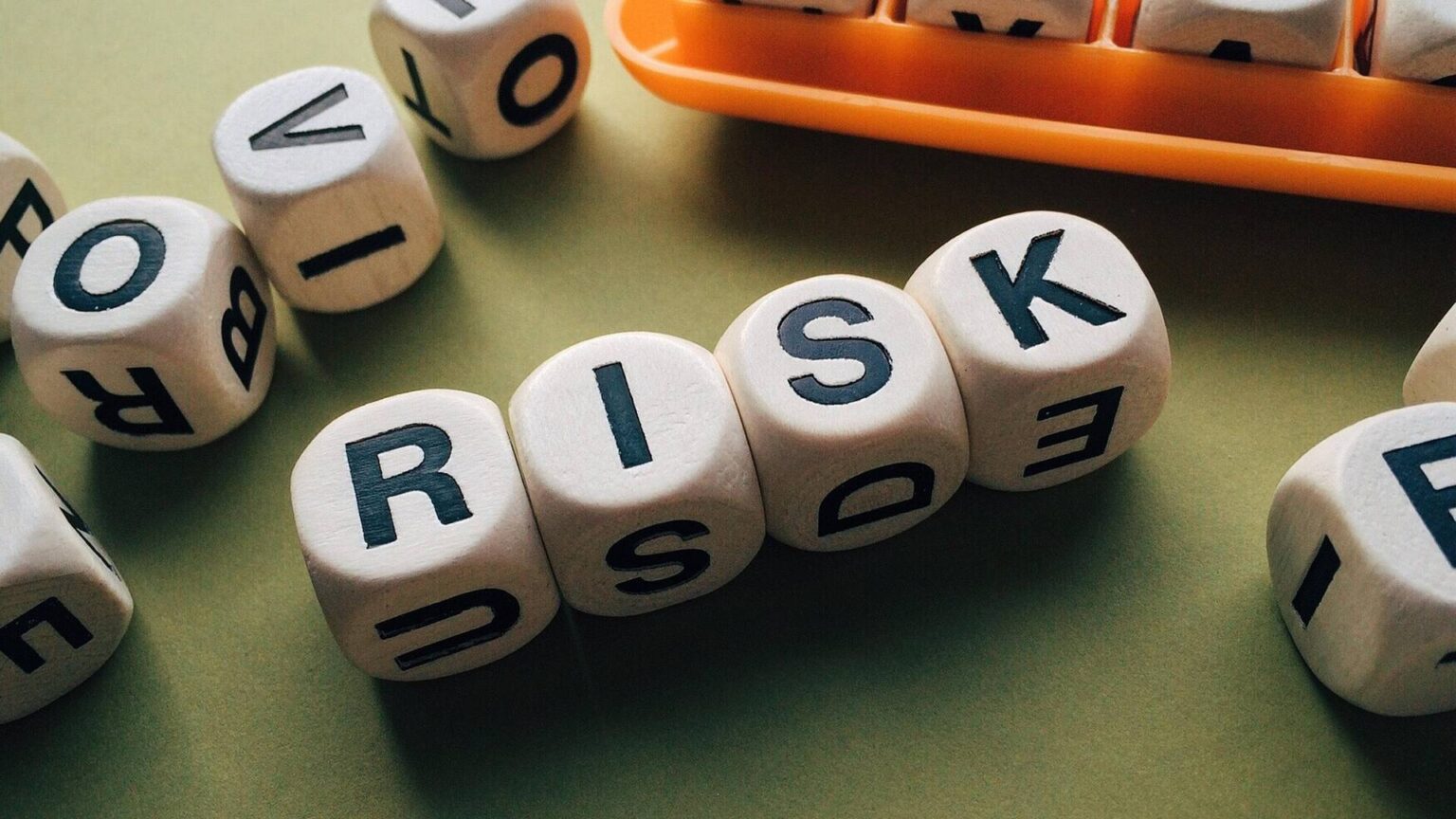 Würfel mit Buchstaben zeigen das Wort "RISK" – Risiko.