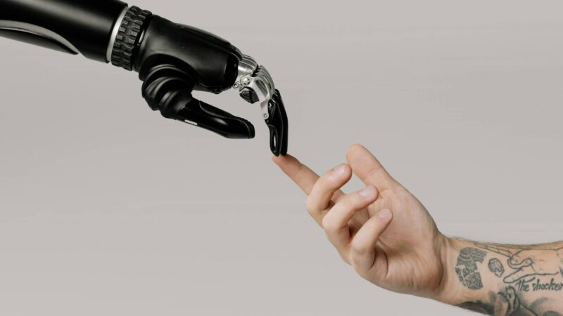 Die Hände eines Manns und eines Roboters berühren sich am Zeigefinger