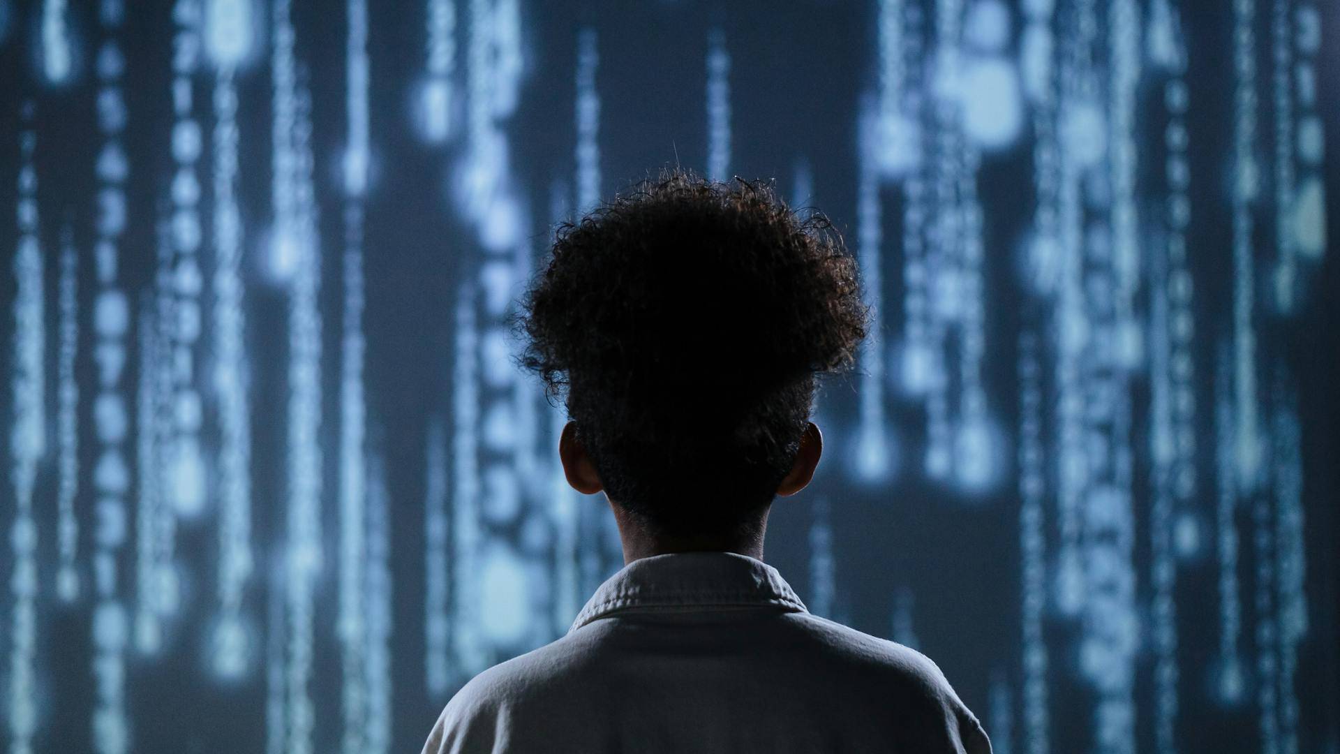Ein Junge steht vor verschwommenen blauen Zahlen wie bei Matrix