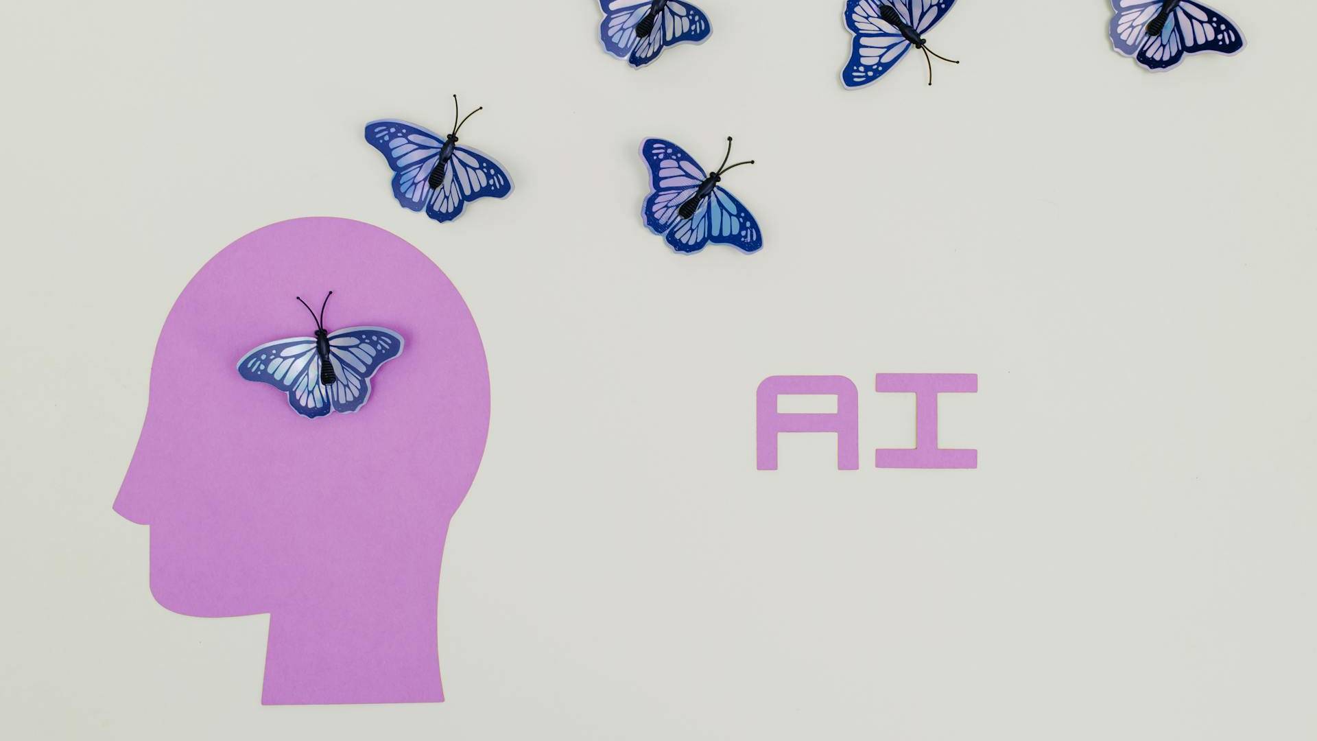 Bunte Schmetterlinge entweichen aus der Silhouette eines Kopfes, neben dem AI steht.